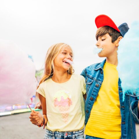 Boy and girl eating sweet cotton at the amusement park